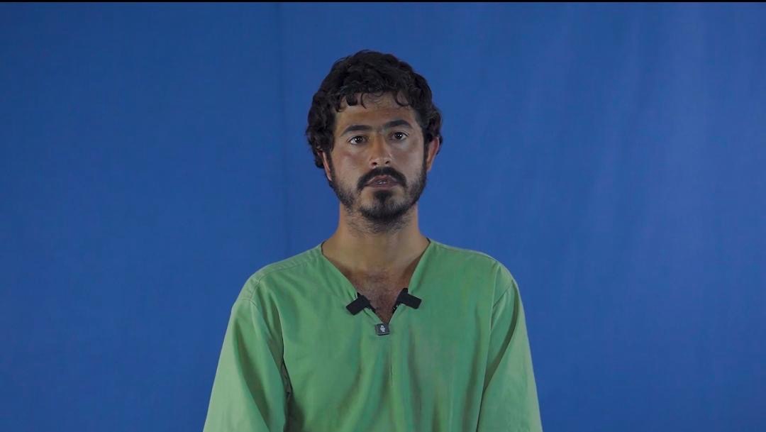 Portrait of Shad Mohammad in a green shirt against a blue background, recorded during detention.