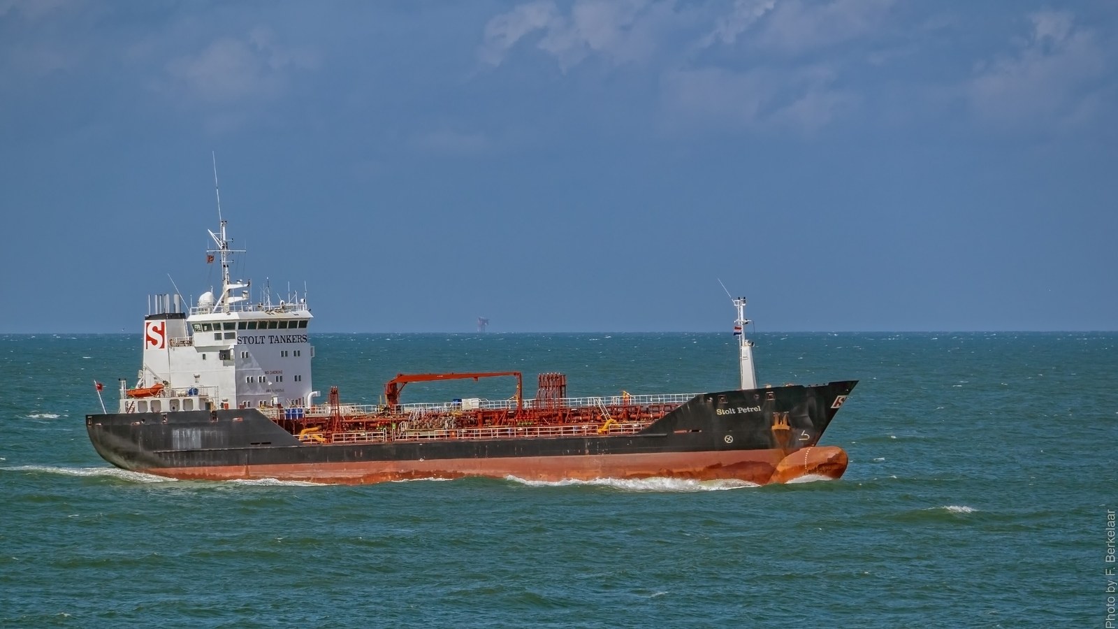 An oil products tanker travels through open water under a clear sky.