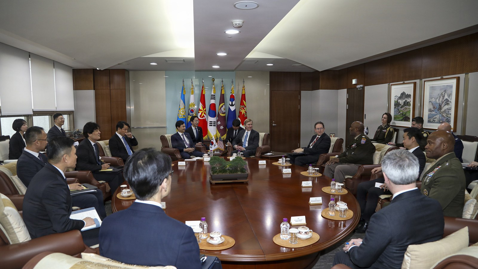 United States and South Korean officials sit around a conference table with both countries’ flags displayed.