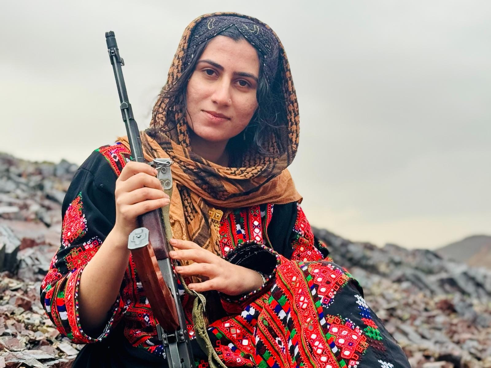 A supplied image shows an armed Baloch woman in traditional dress, reflecting the interview’s focus on women’s visibility and leadership within Baloch armed resistance.