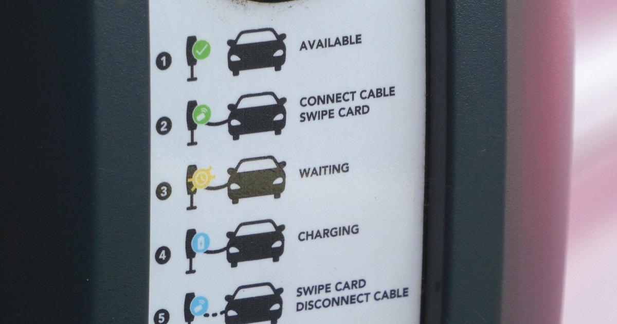 Close view of an electric-vehicle charging station and attached charging cable.