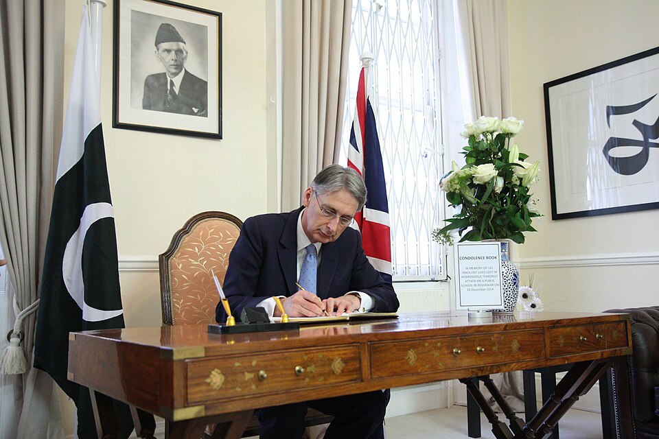 A UK foreign secretary signs a book inside the Pakistan High Commission in London in an archive diplomatic photograph.