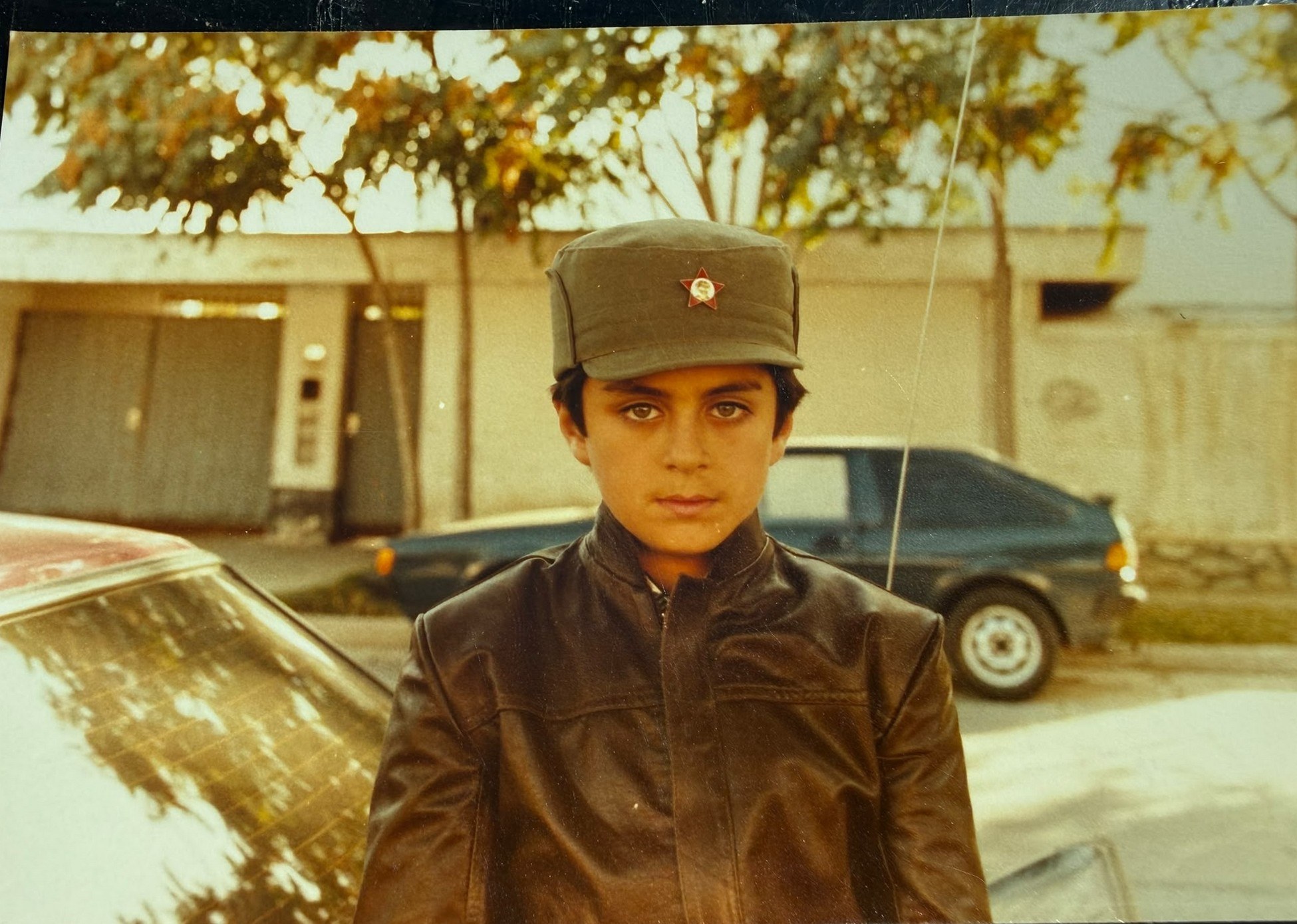 A young Mehran Marri Baloch in a cap and leather jacket, standing on a street in Kabul.