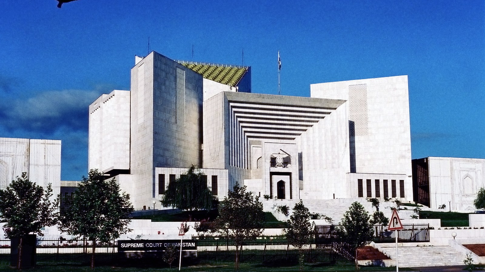The facade of the Supreme Court of Pakistan in Islamabad beneath a blue sky.