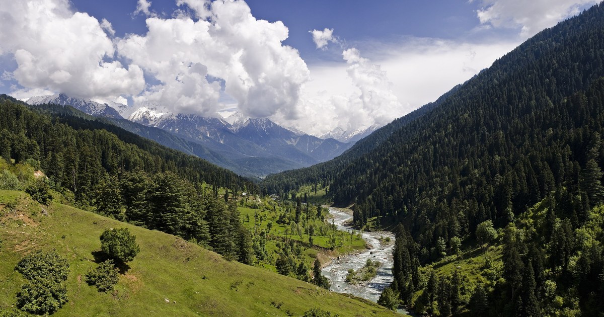 A broad Himalayan valley near Pahalgam in Jammu and Kashmir, with green slopes and high mountains under a pale sky.