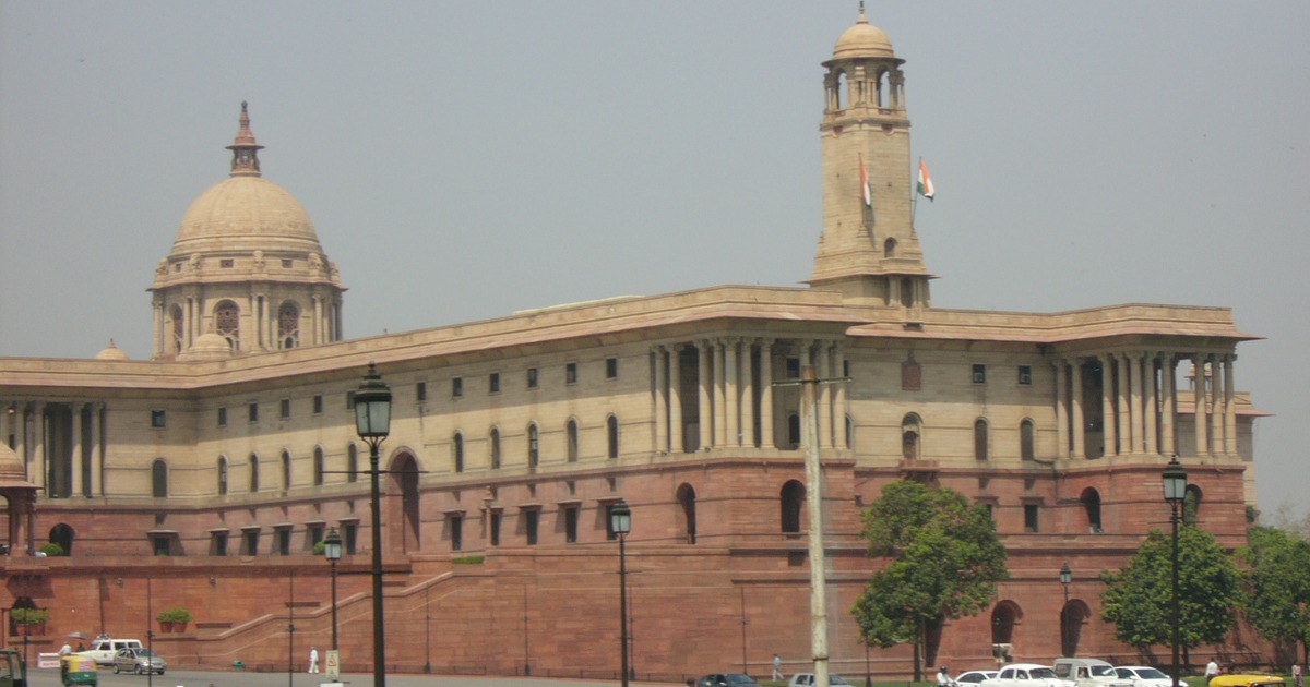 The Parliament of India building in New Delhi beneath a blue sky.