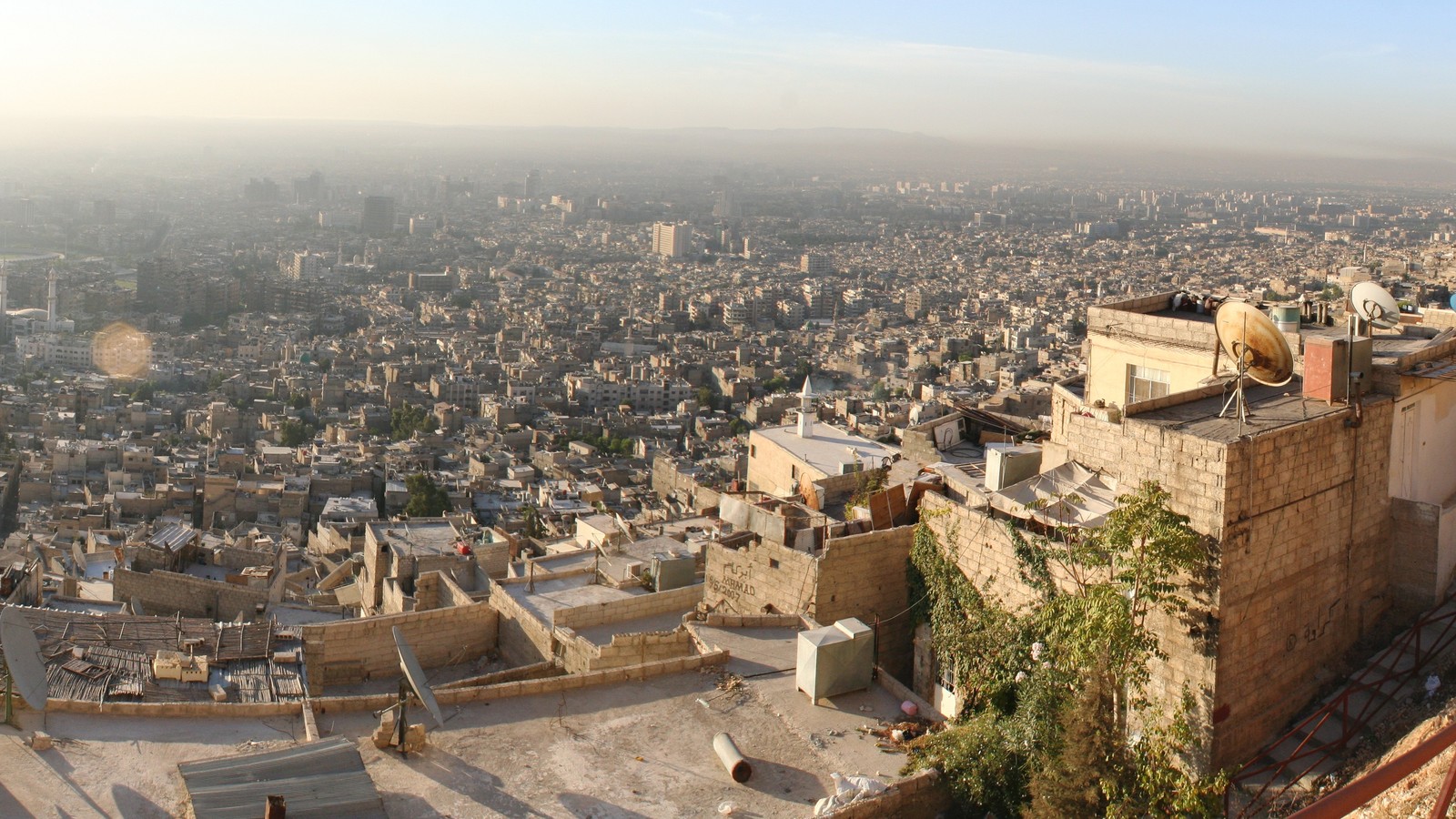 A city view of Damascus with buildings and hills visible in the distance.