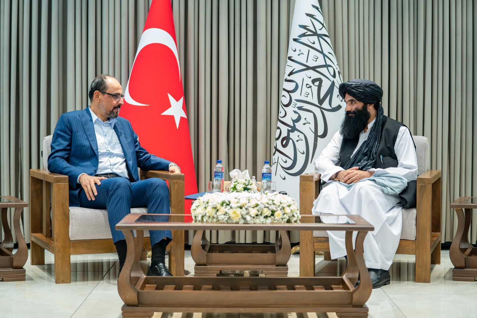 Ibrahim Kalın and a Taliban official standing side by side in Kabul with the Turkish and Taliban flags behind them.