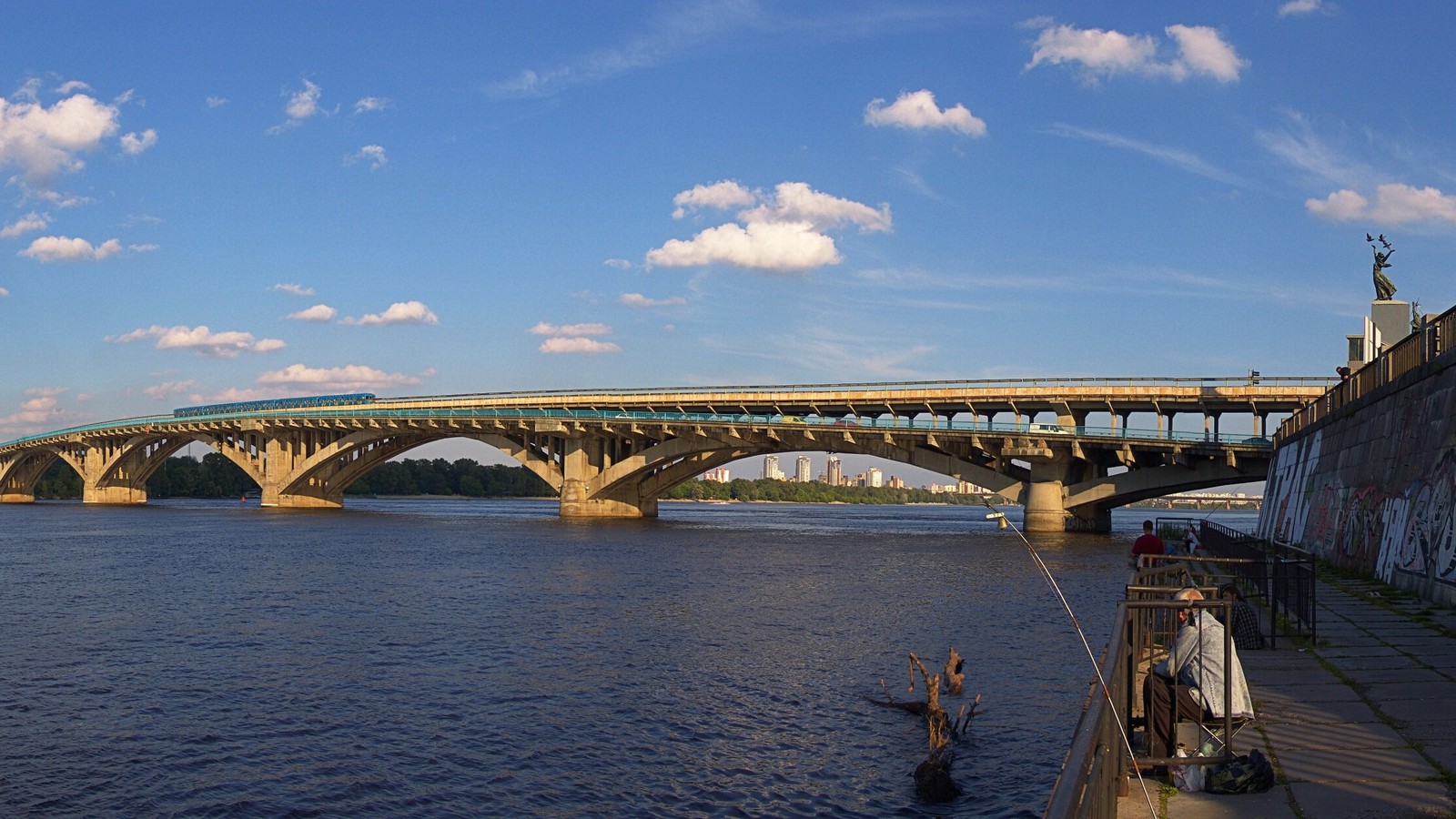 A broad view of Kyiv with urban buildings and the Dnipro river visible.