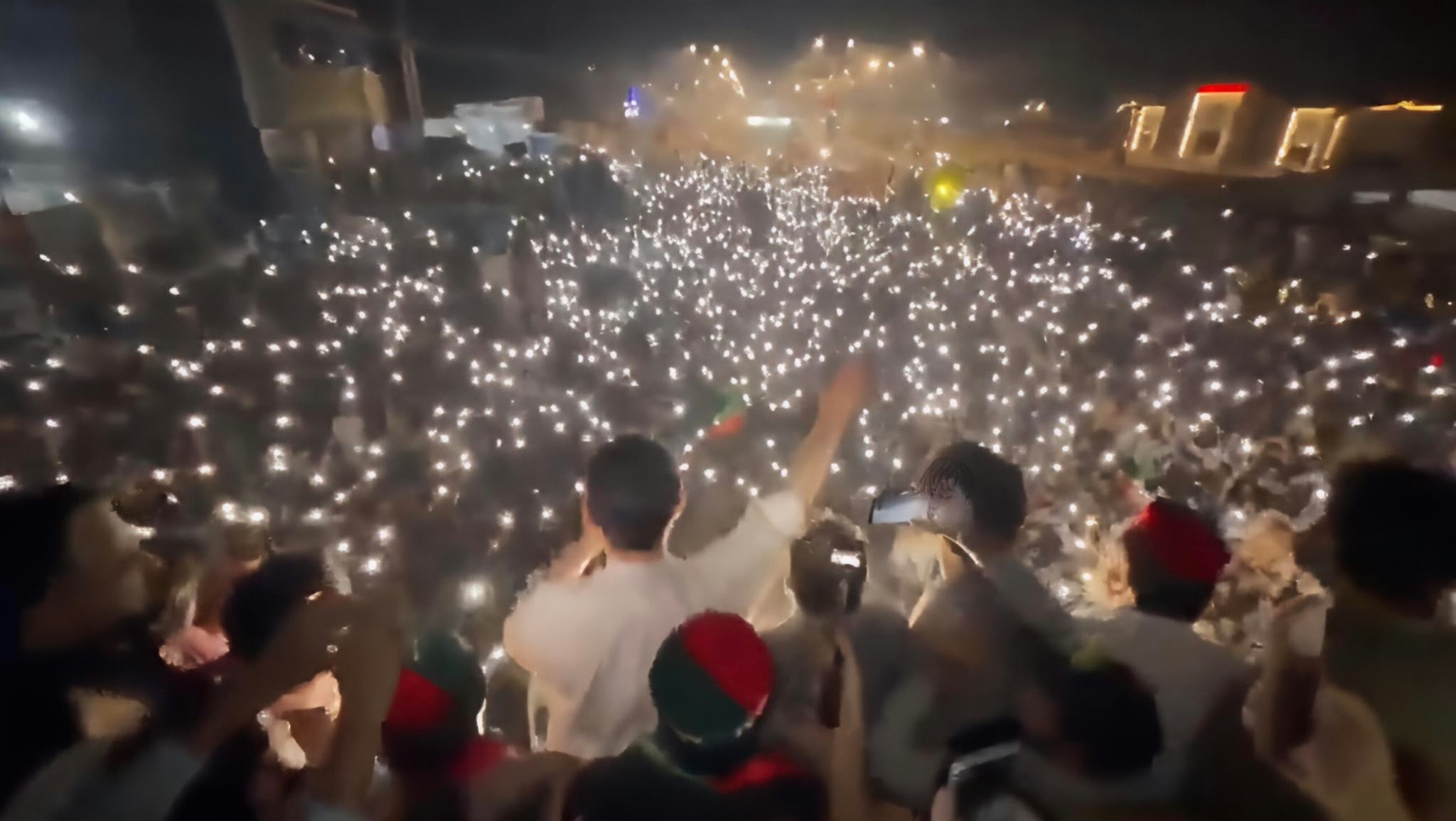 A large nighttime crowd in Khyber Pakhtunkhwa holds up phone lights during a protest.